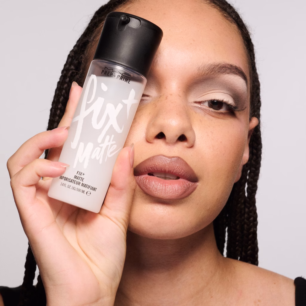 Woman holding MAC Prep + Prime Fix+ Setting Spray infront of her eye