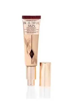 Charlotte Tilbury Beautiful Skin Foundation in its rose gold tube, placed on a vintage-style vanity.