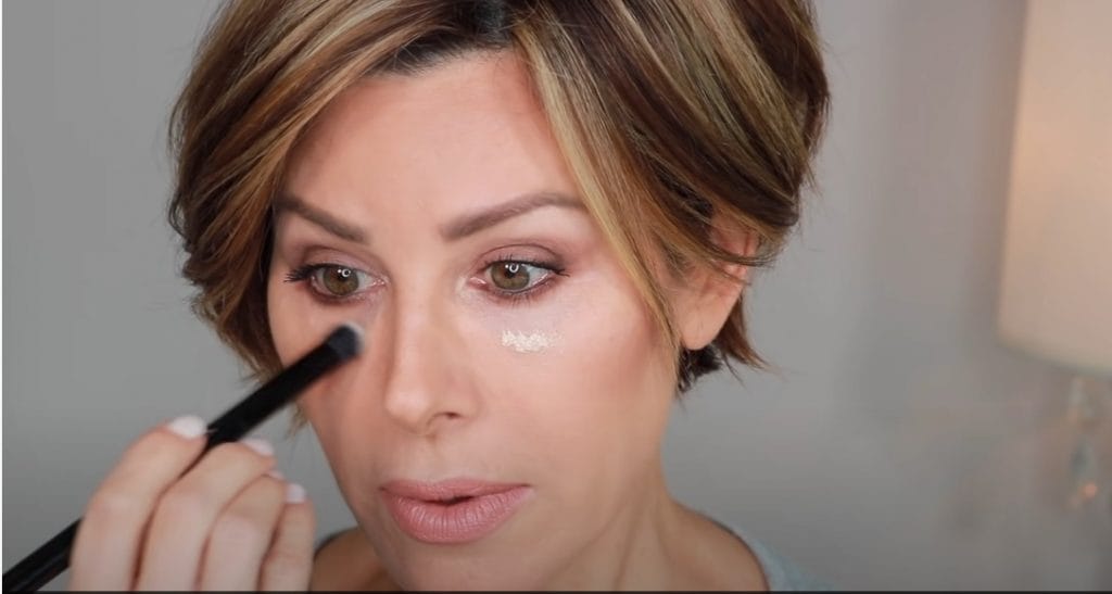 Mature woman applying concealer