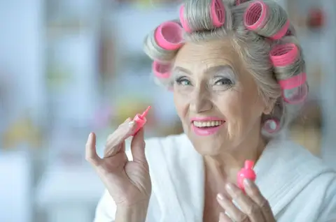 Mature woman applying lipstick