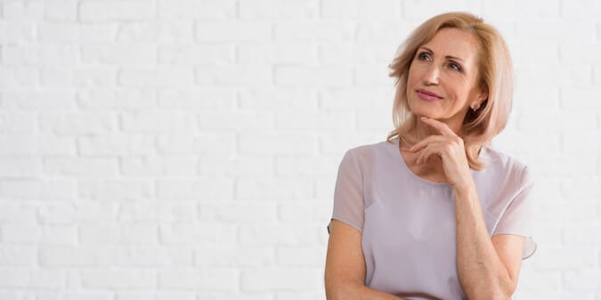 Smiling mature woman touching her face while admiring her smooth, healthy skin — symbol of confidence and glow after 50.