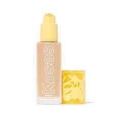 Kosas Revealer Foundation bottle with bold lettering, surrounded by skincare and makeup essentials.