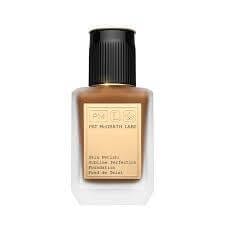 Pat McGrath Sublime Perfection Foundation bottle with luxurious gold detailing on a vanity table.