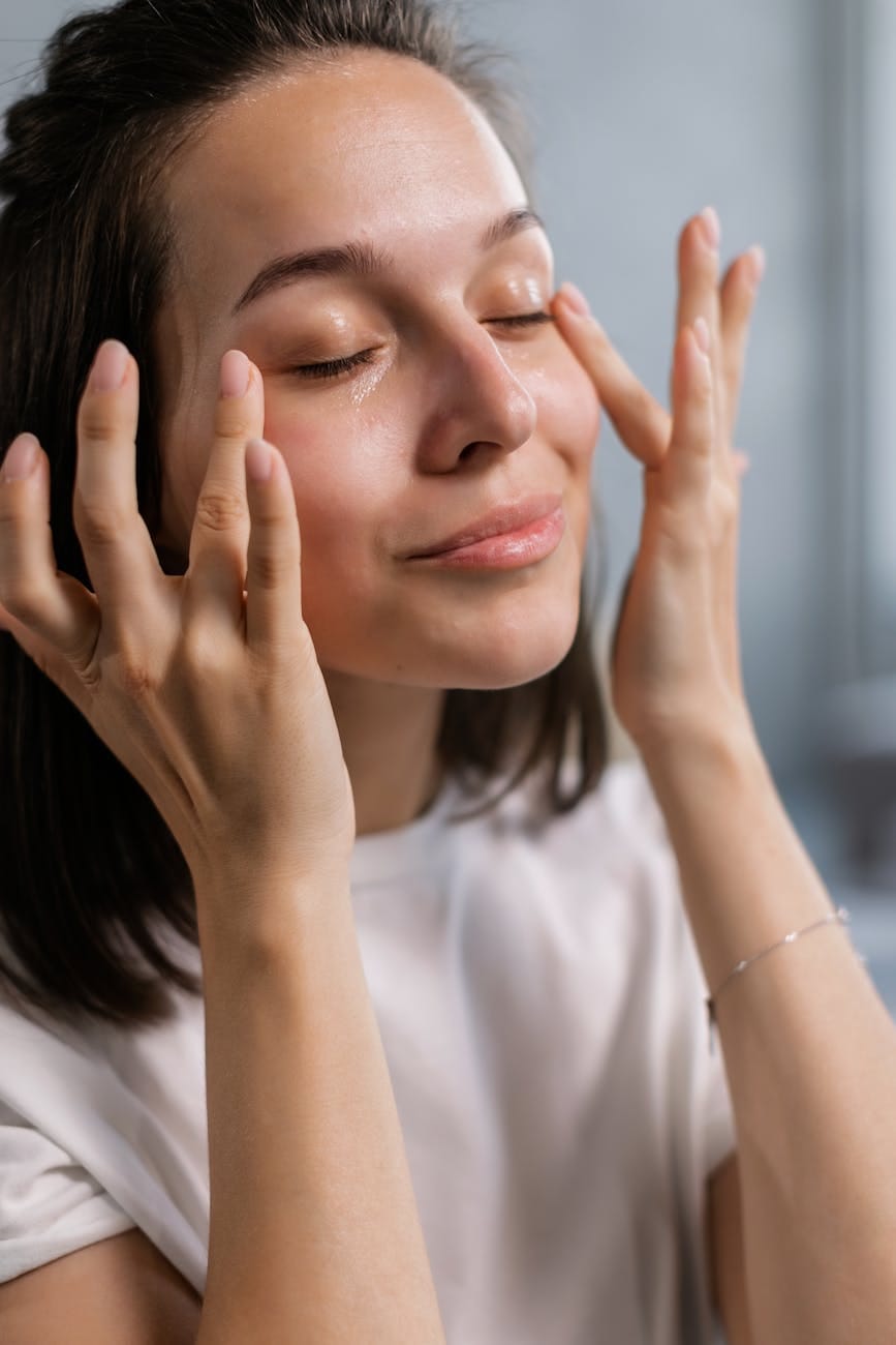 a woman in white shirt patting the sides of her eyes with Tinted Moisturizers