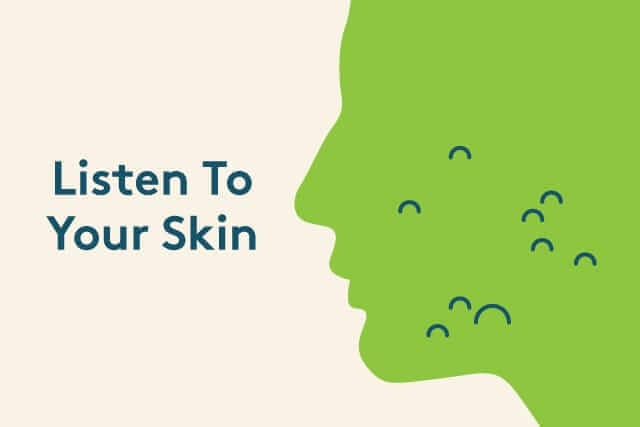 Woman examining skin in mirror thoughtfully, depicting listen to your skin’s needs for personalized skincare over 50.