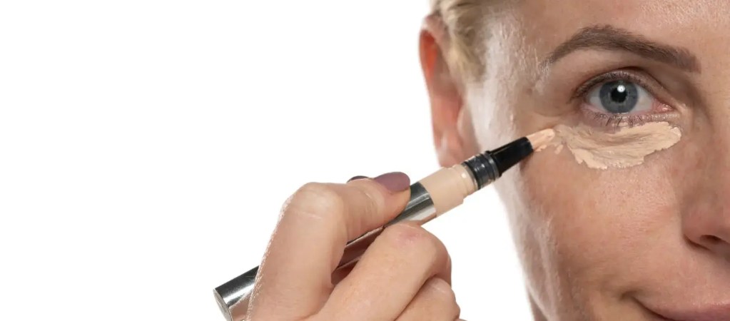 Mature woman applying concealer