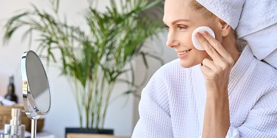 Mature woman removing makeup infront of mirror